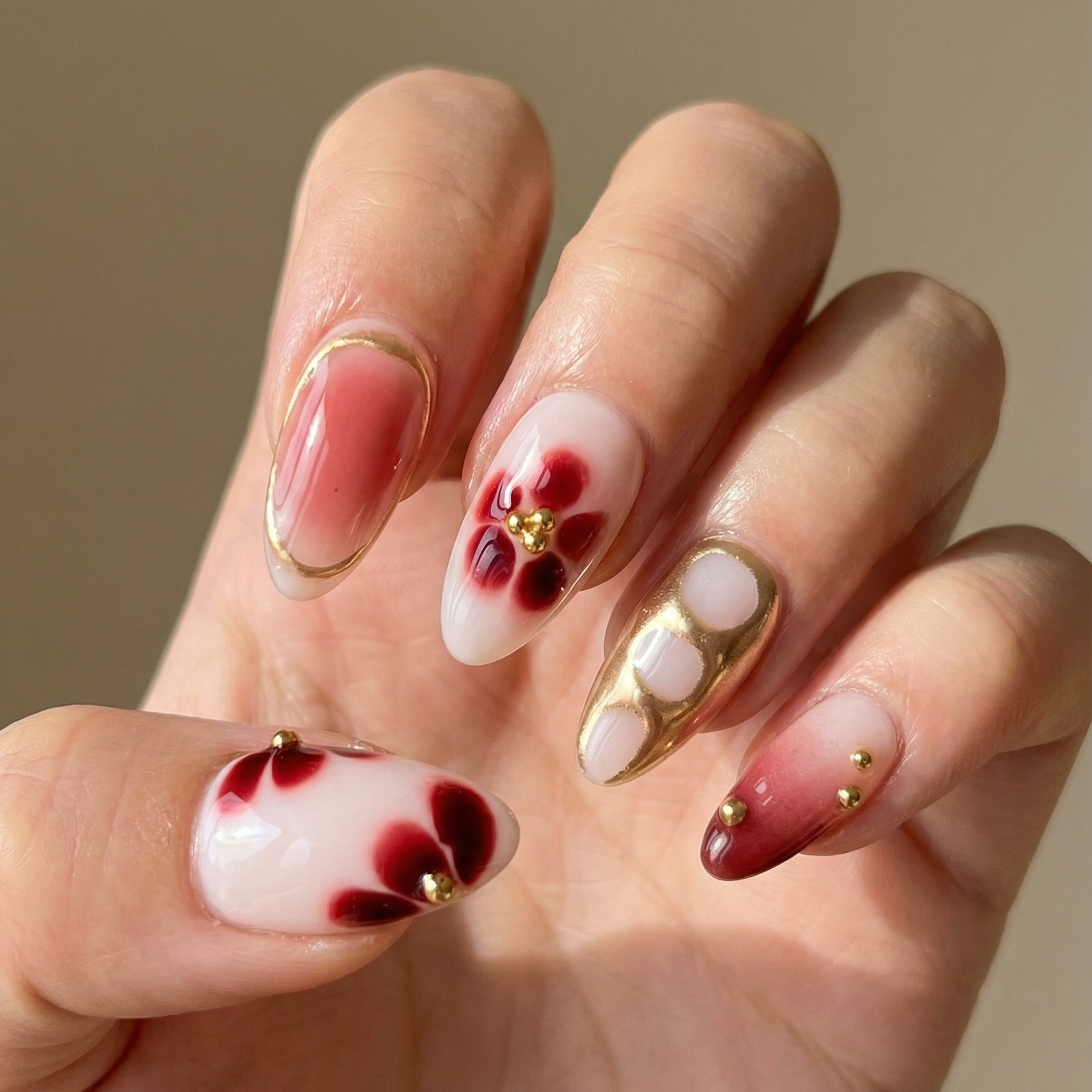Hand with red and white floral nail art on a beige background