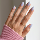 Hand with light purple nail polish wearing a pink sleeve against a neutral background