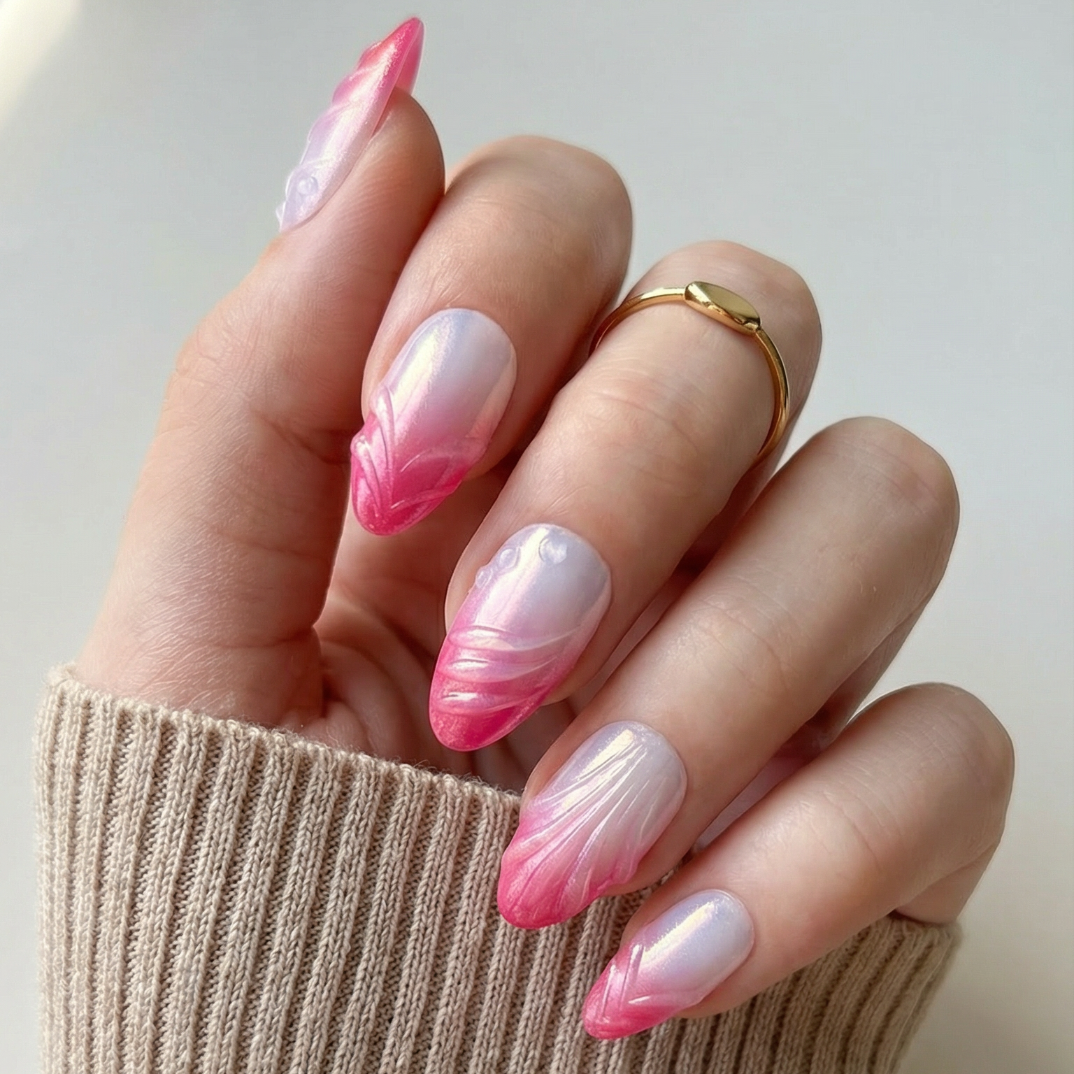 Hand with pink and white gradient nails wearing a beige sleeve.